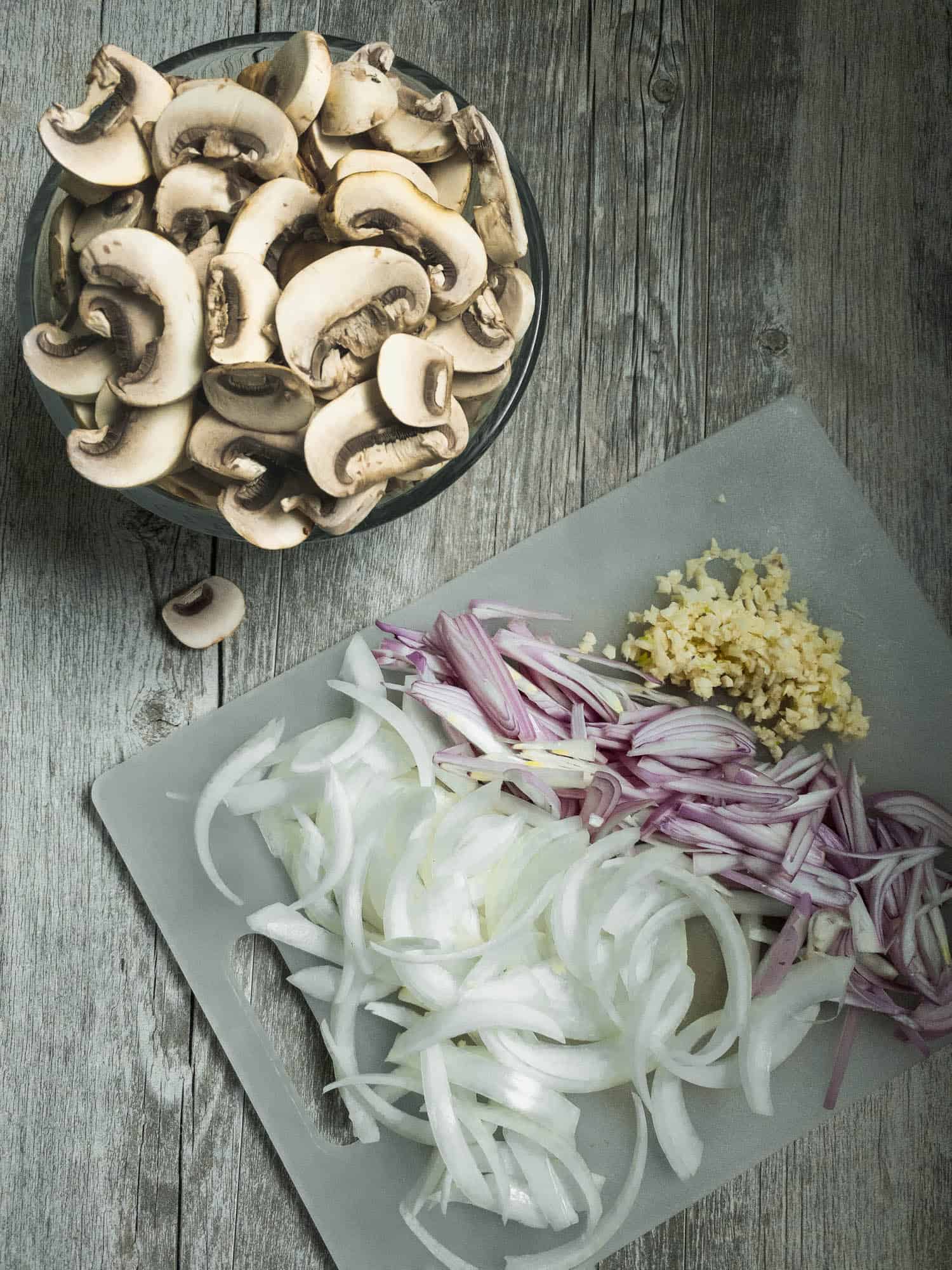chopped mushrooms and onions on a cutting board