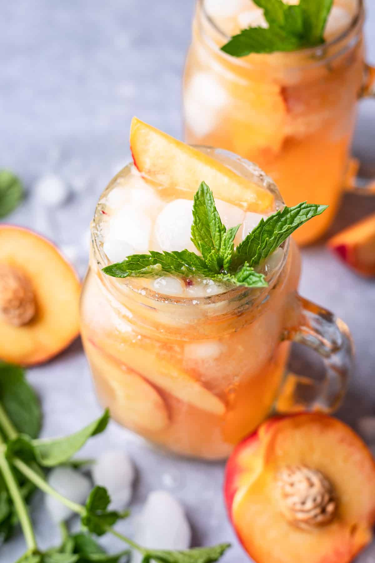 Fresh mint and peach slices on top of a bourbon peach smash.