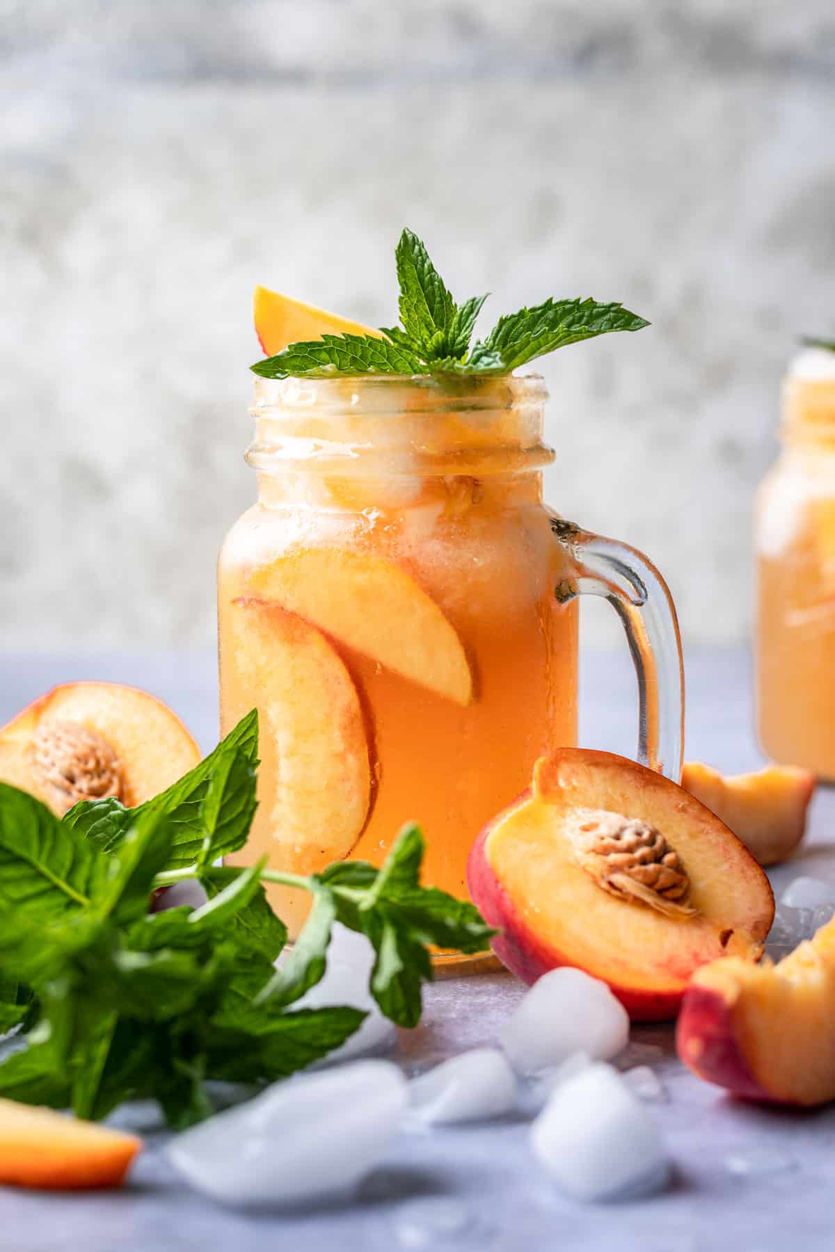 Bourbon peach smash in a glass garnished with fresh mint and peach slices.