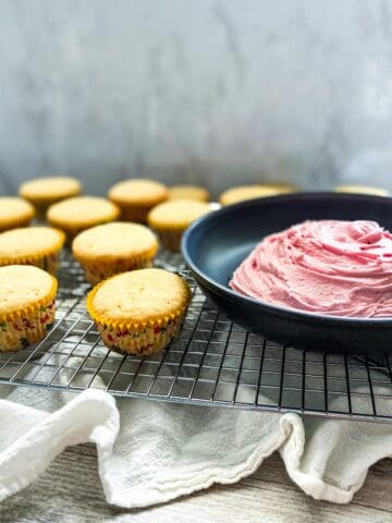 plain cupcakes with strawberry buttercream frosting in a bowl