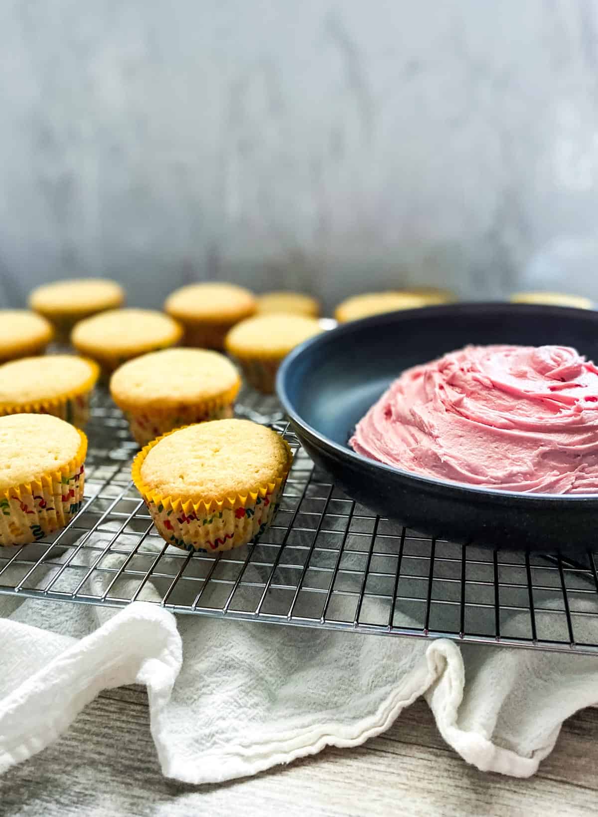 plain cupcakes with strawberry buttercream frosting in a bowl