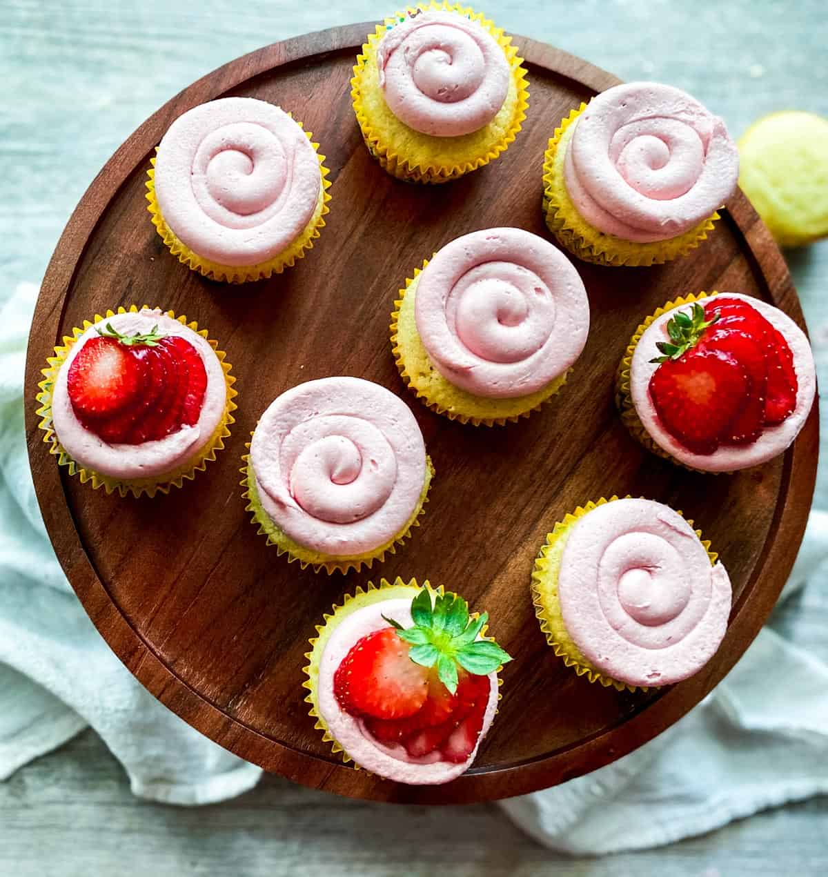 almond cupcakes with frosting on a wooden cake stand