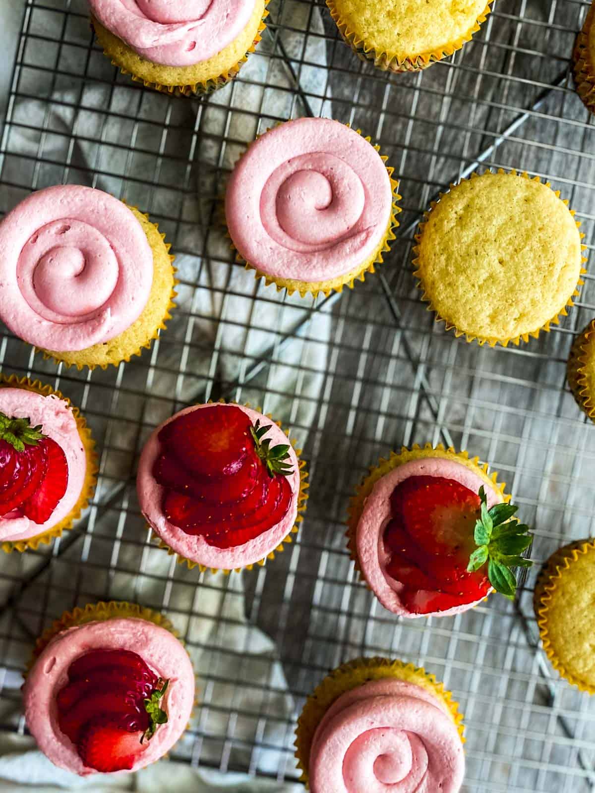 cupcakes with strawberry frosting on a cooling rack