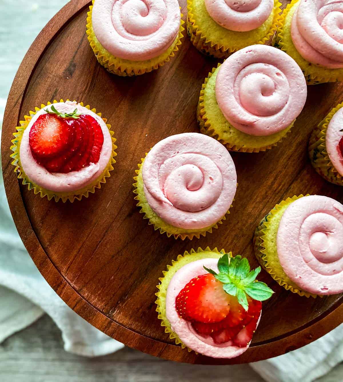 almond cupcakes with frosting on a wooden cake stand