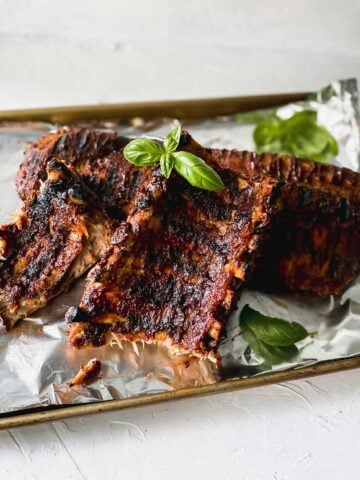 bbq baby back ribs on an aluminum foil covered sheet pan