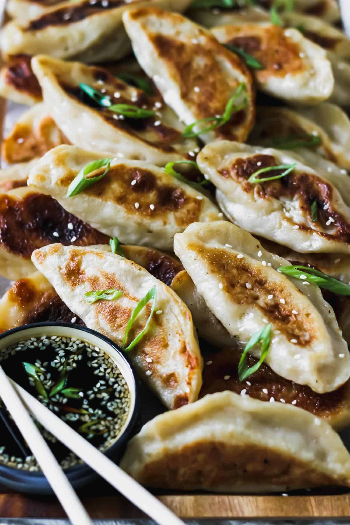 Close up of chinese chicken dumplings with sesame soy sauce and scallions.