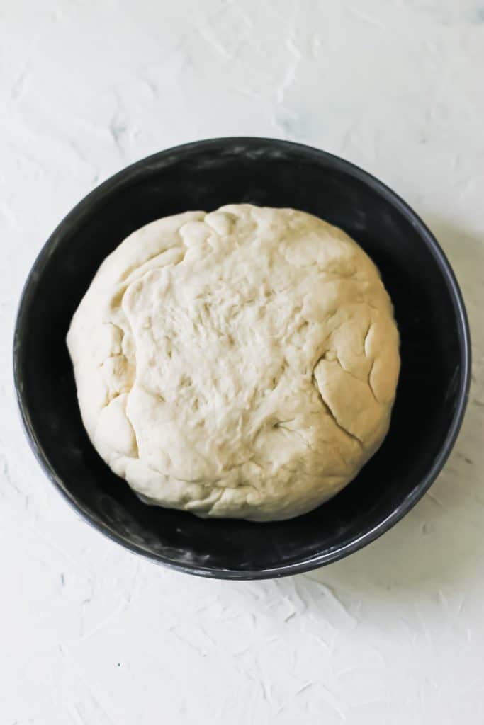 A ball of dumpling dough in a black bowl.