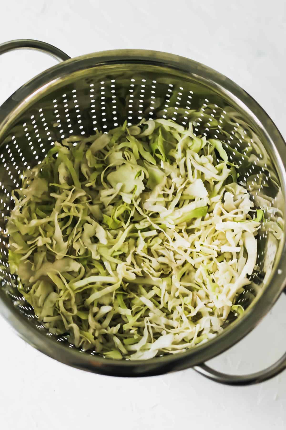 Water chestnuts, salt, and cabbage in a silver colander.