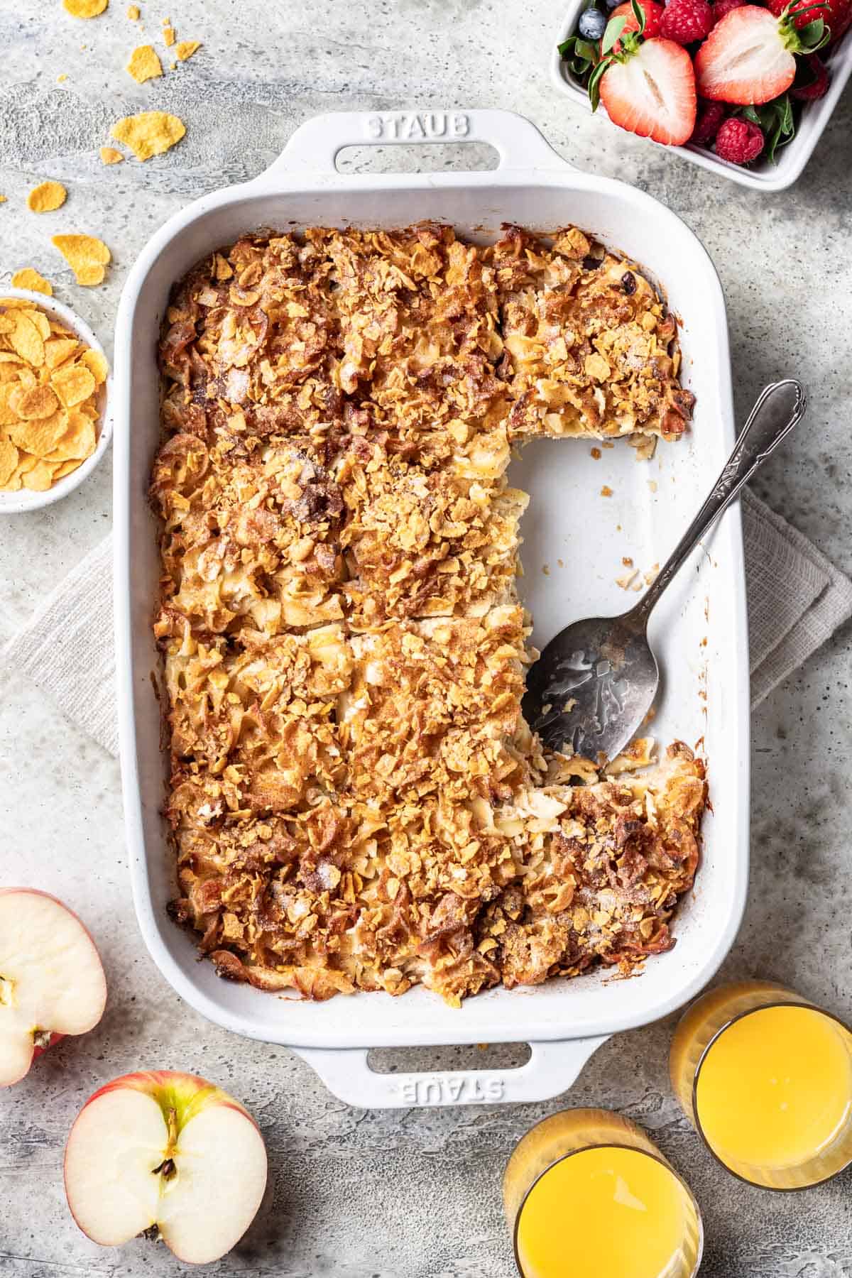 Cinnamon apple noodle kugel in a baking dish with 2 pieces missing.
