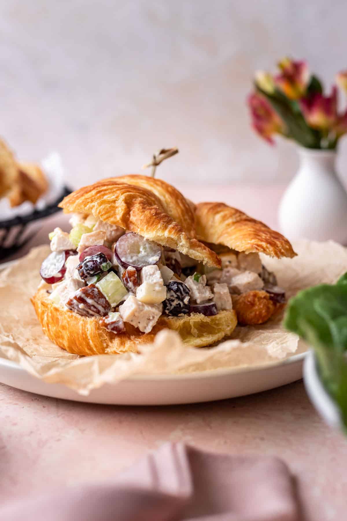 Chicken salad on a croissant with a toothpick sticking out the top.