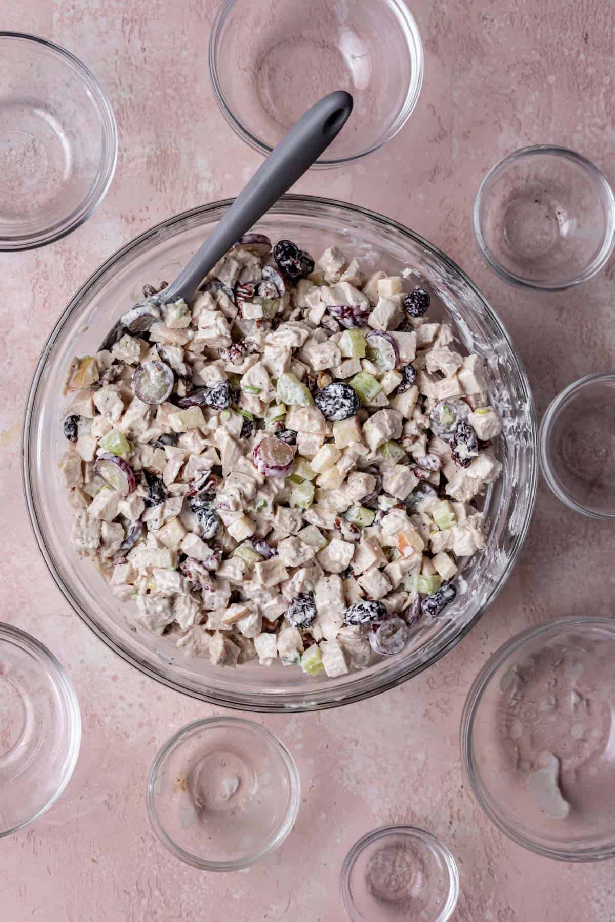 Chicken salad mixed with mayonnaise in a glass mixing bowl.