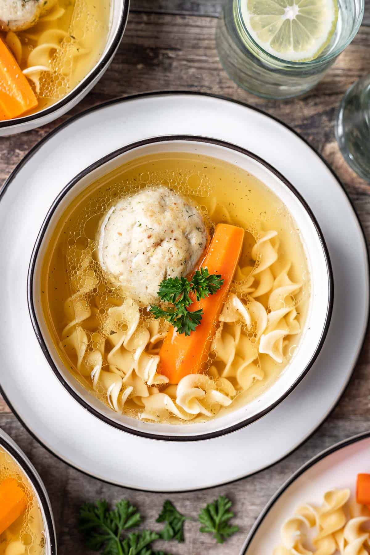 Instant pot matzo ball soup in a bowl with a cooked carrot and egg noodles.
