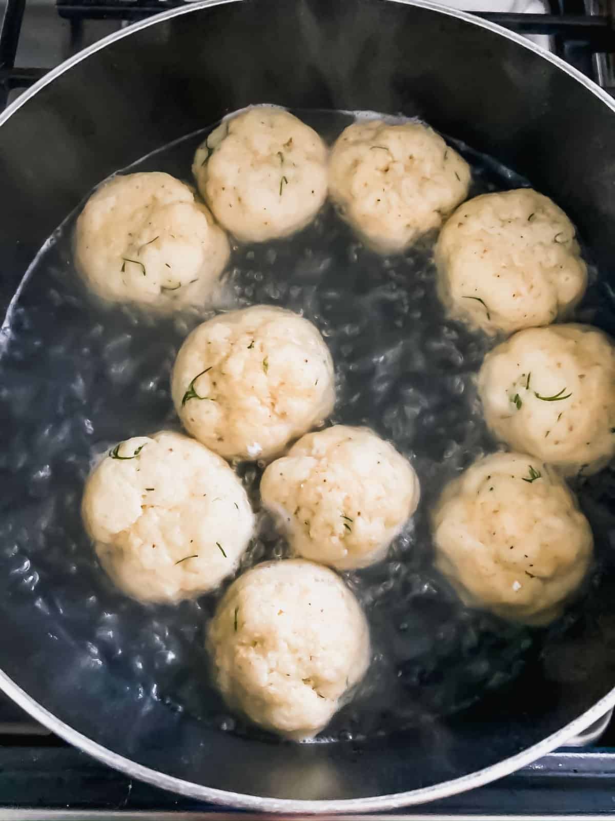 matzo balls in a black pot of boiling water
