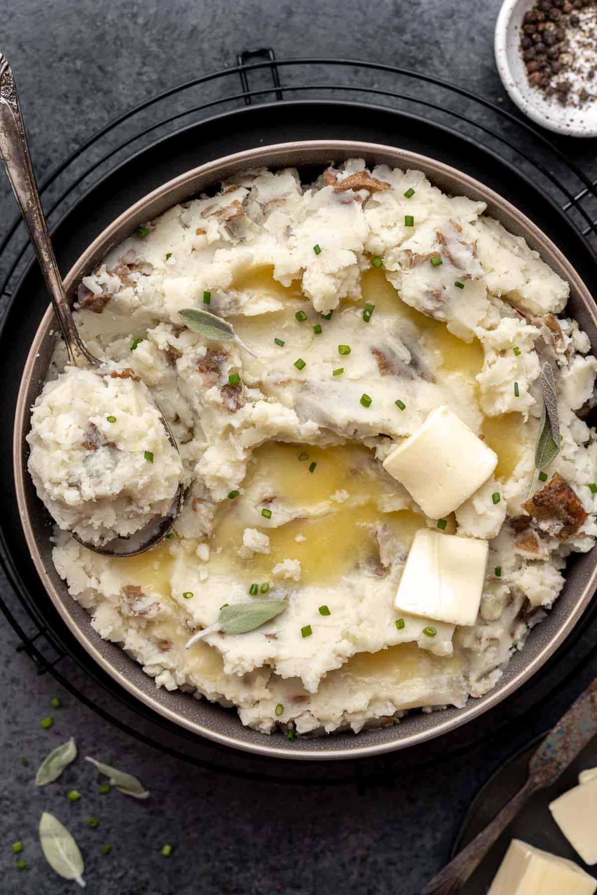 Fluffy almond milk mashed potatoes in a serving bowl with melted butter and a serving spoon.