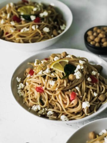 Mediterranean garlic and olive oil pasta in 3 white bowls with garbanzo beans on the side.