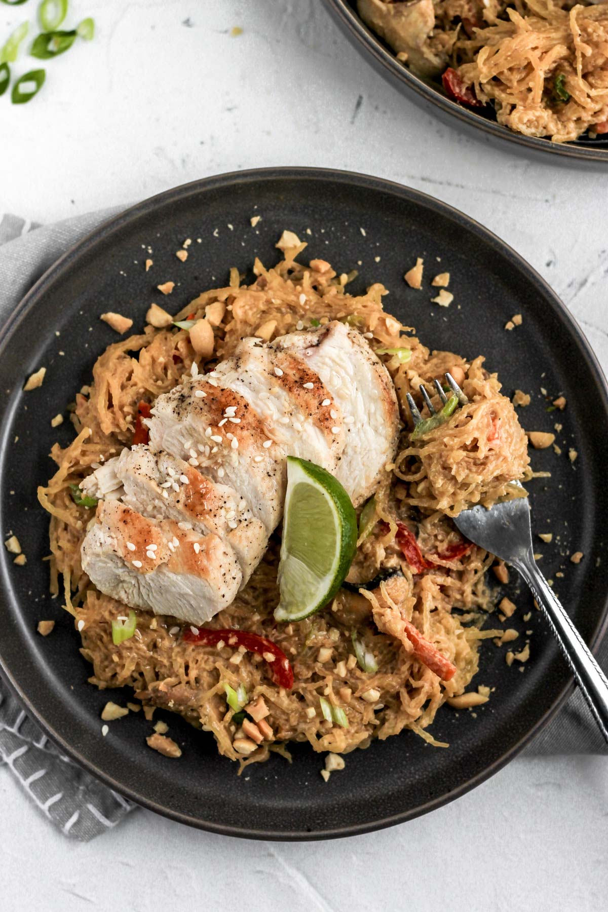 Thai peanut spaghetti squash on a dark gray plate with a fork full.