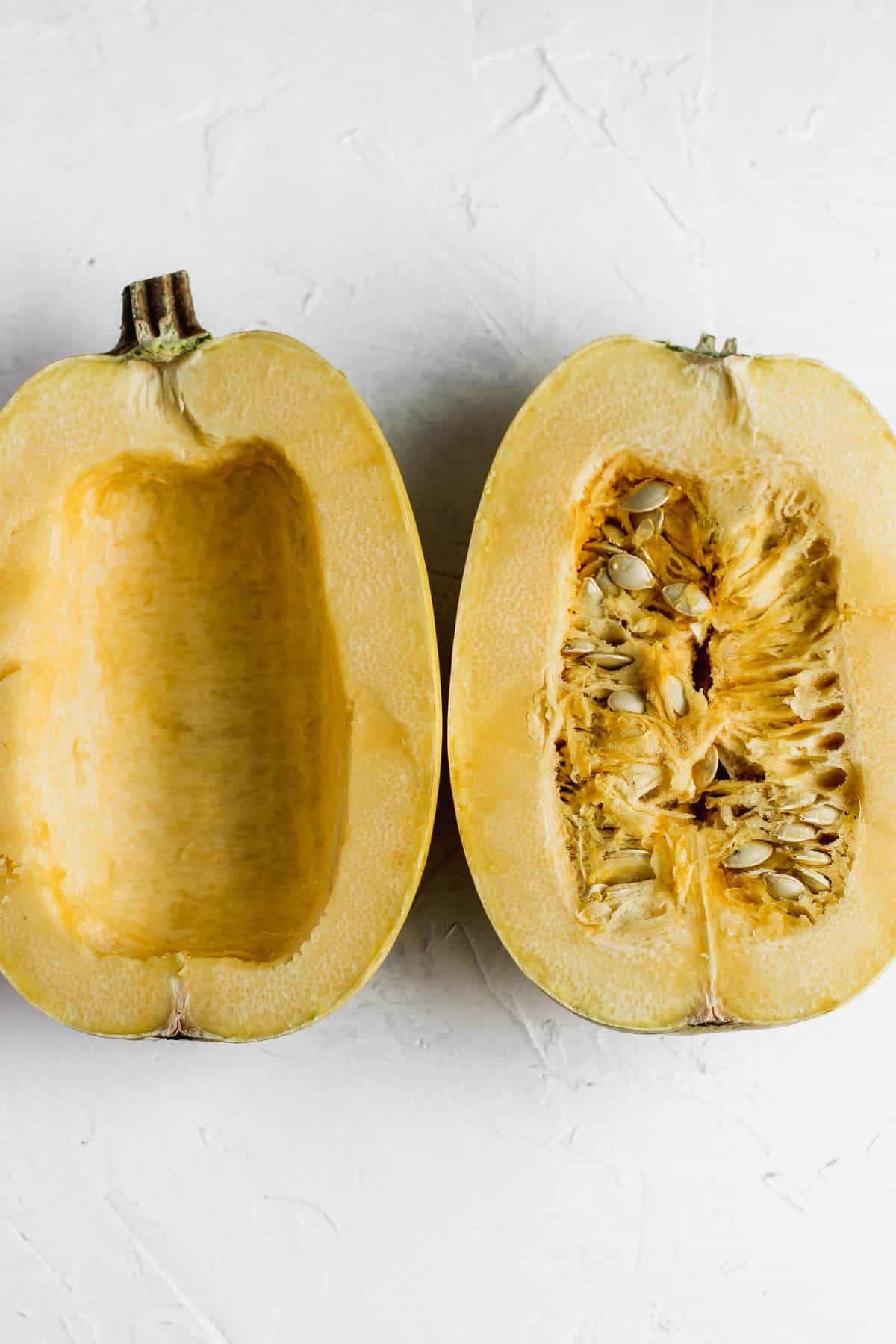 Halved uncooked spaghetti squash with seeds and inners still intact.