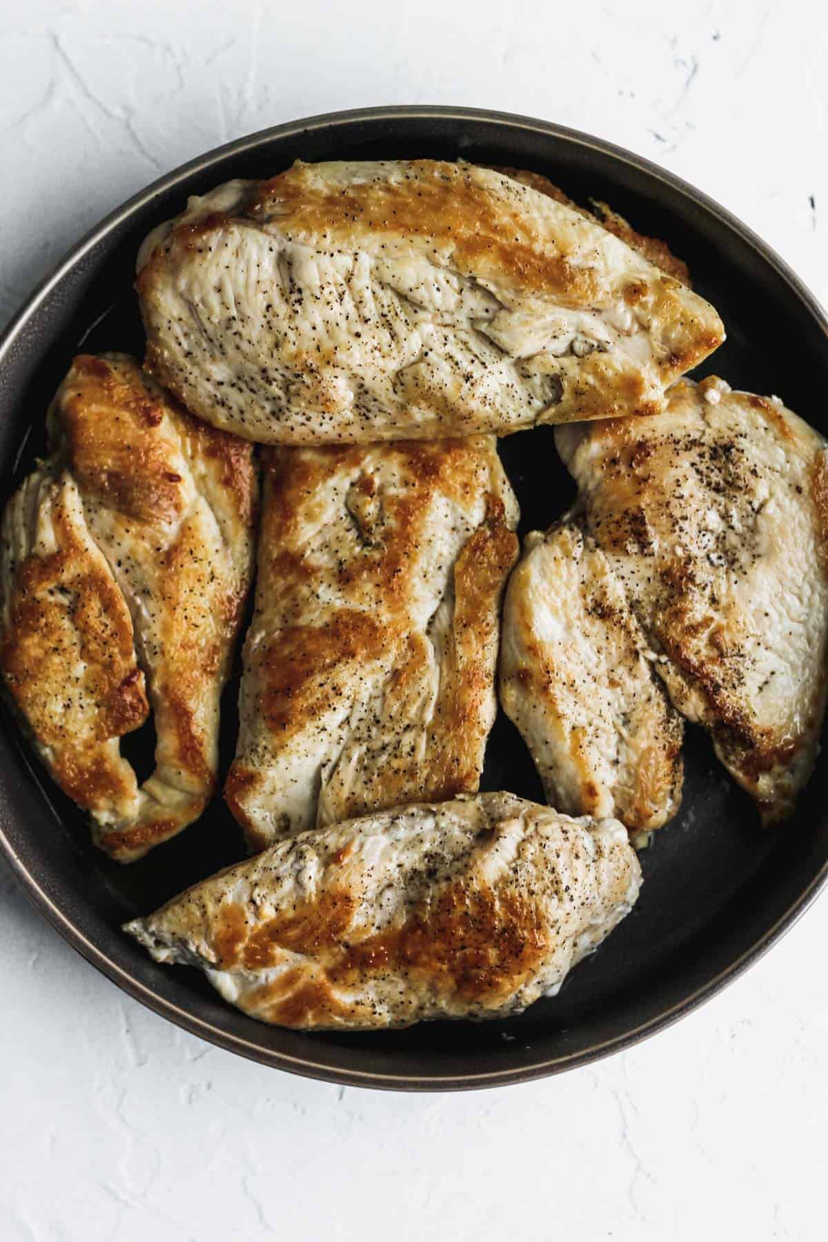 Browned and cooked chicken on a dark gray plate.