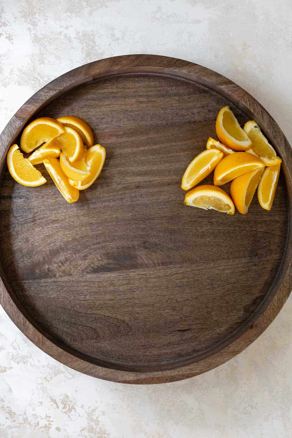 Orange wedges arranged on a wooden board.