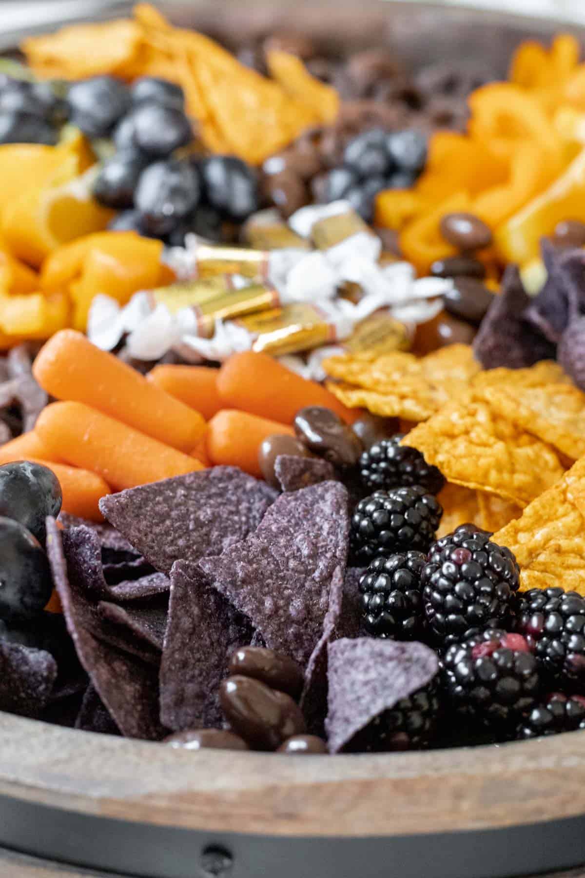 A closeup view of all the orange and "black" foods arranged on a wooden board.