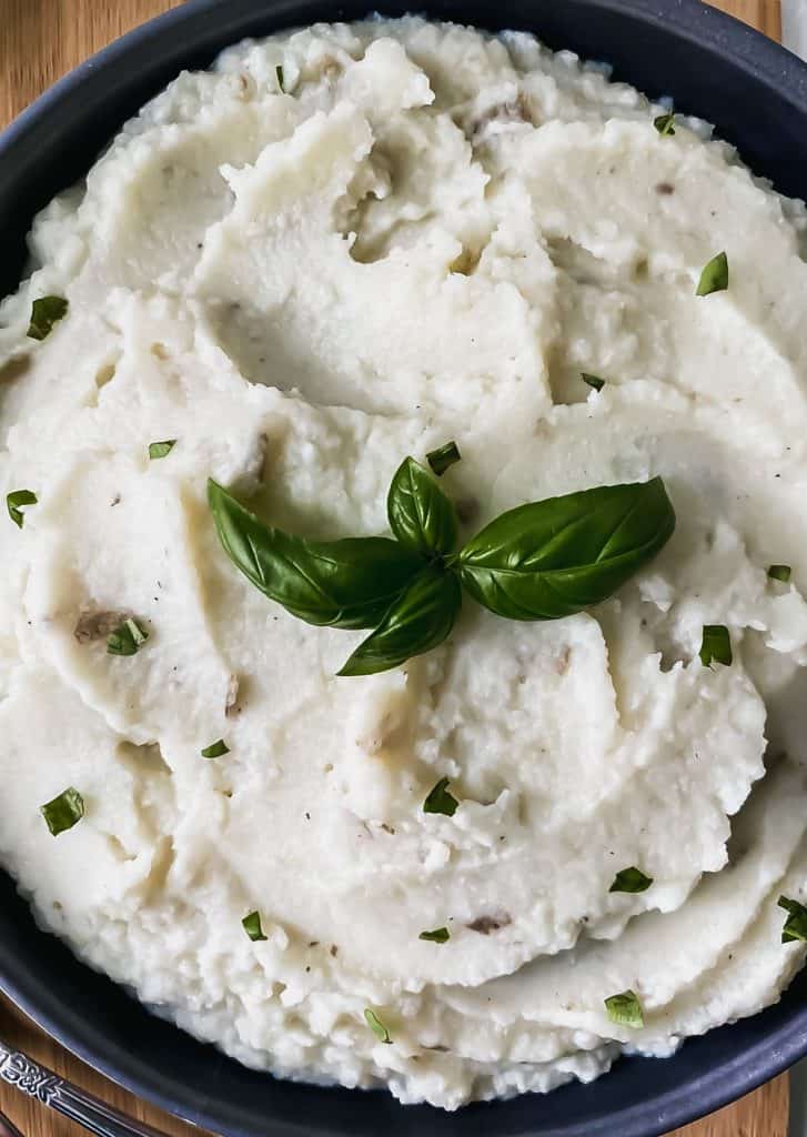 Close up of cauliflower mashed potatoes in a black bowl.