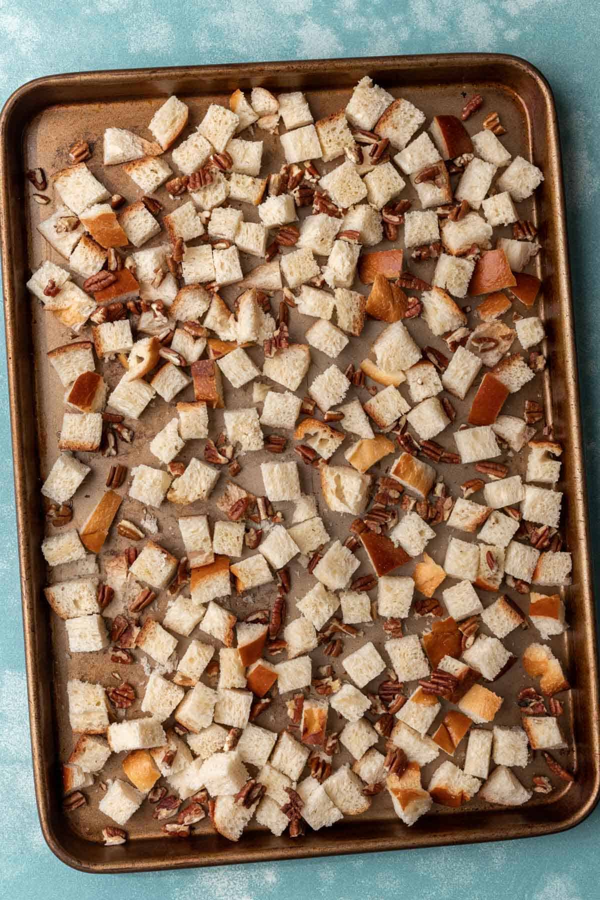 Cubed challah and pecans on a sheet pan before going in the oven.