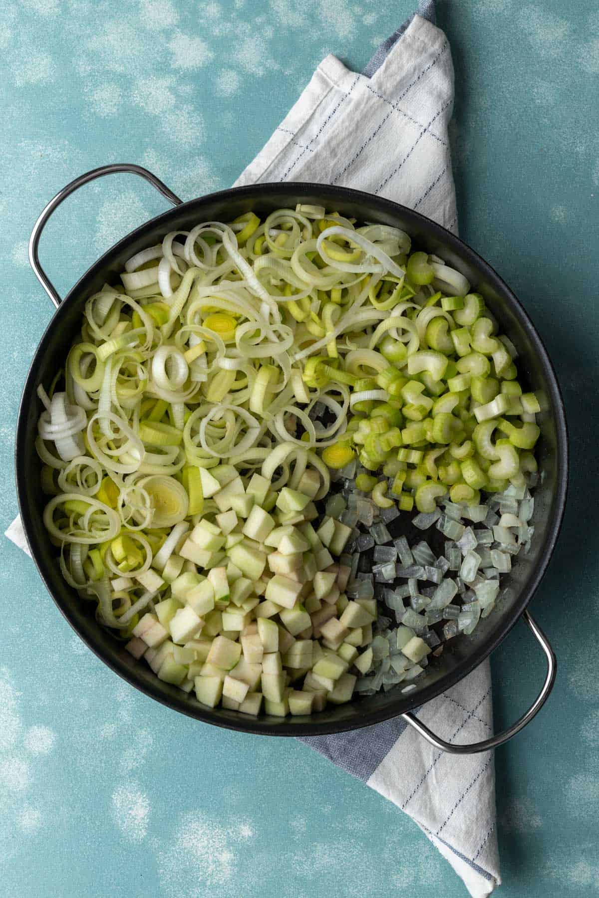 Onions, apple, celery, and leeks in a large skillet.