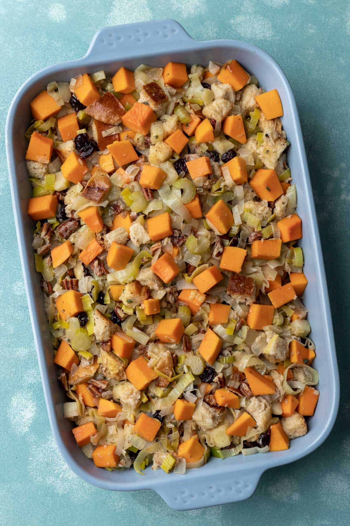 Uncooked stuffing in a blue baking dish before going in the oven.