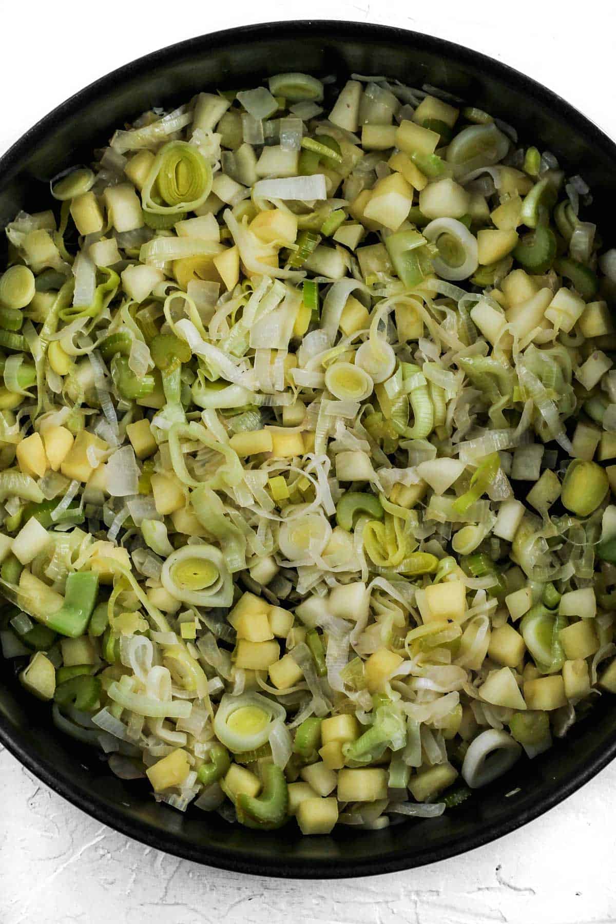 Cooked leeks, apples, and celery in a skillet.