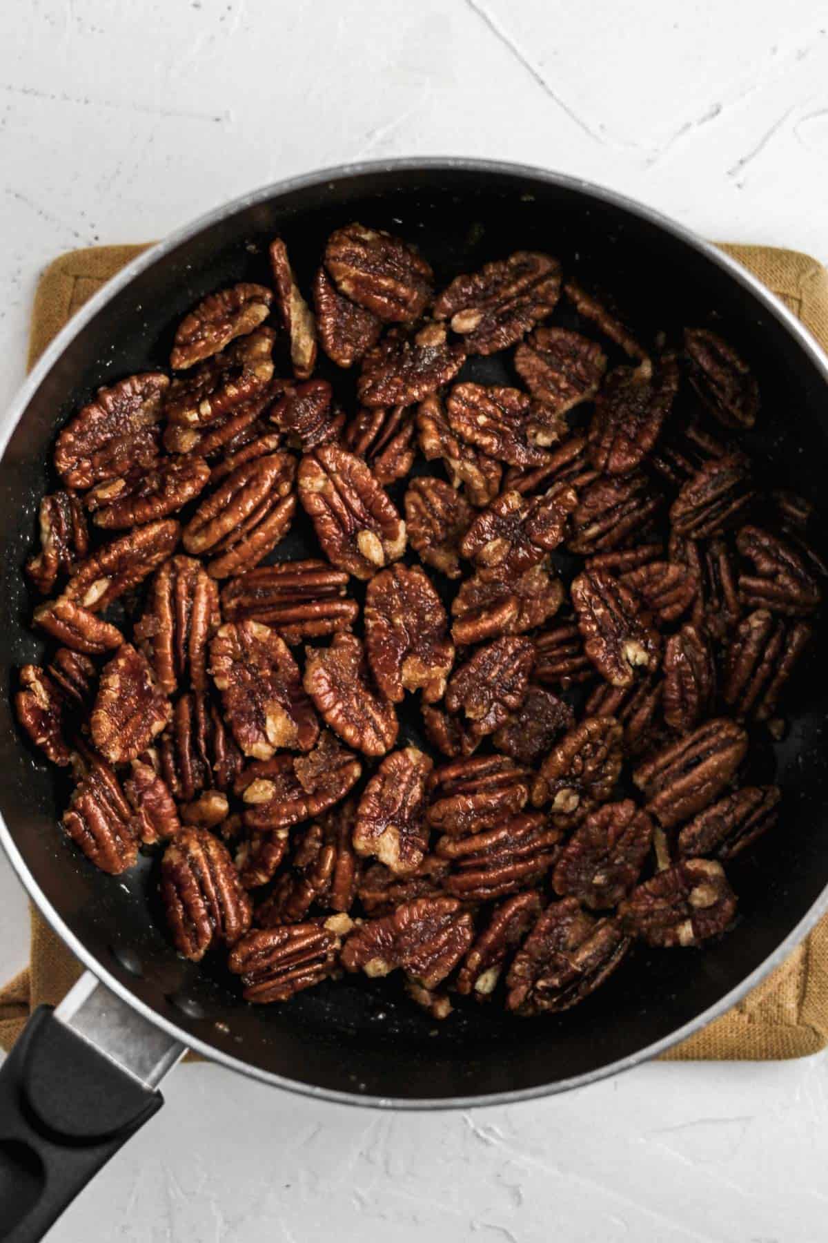 Pecans cooking a black saucepan.