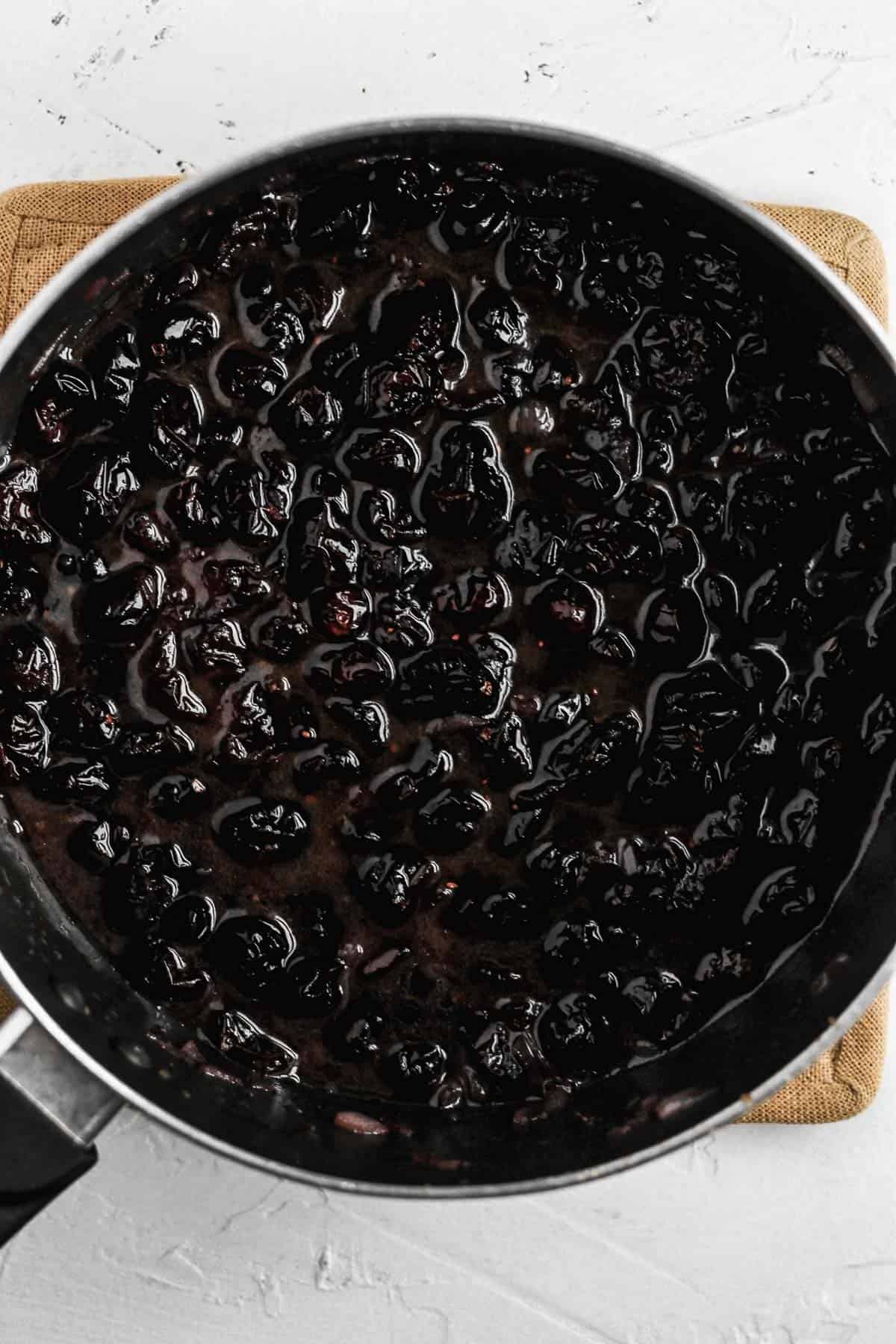 Warm cranberry vinaigrette cooking in a black saucepan.