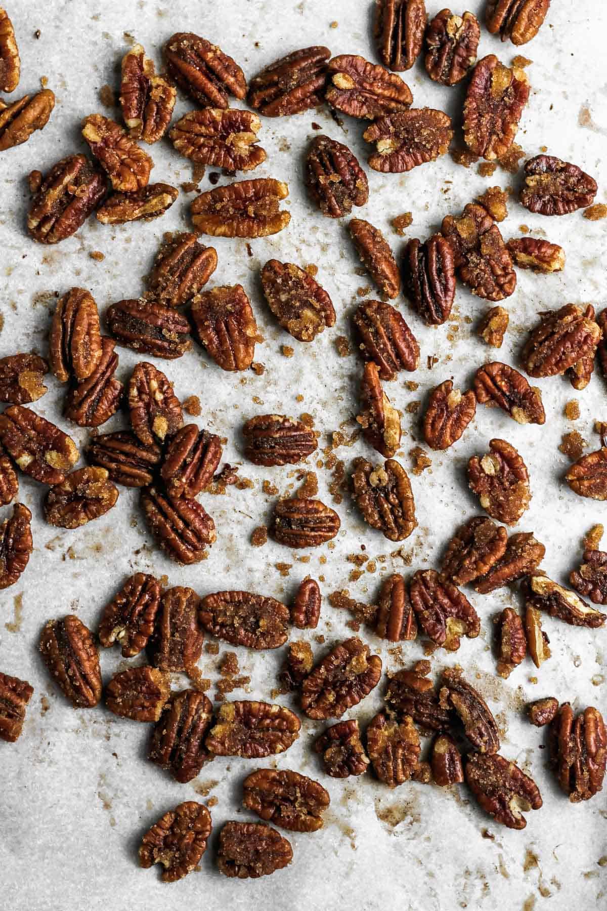 Candied pecans on a sheetpan covered with parchment paper.