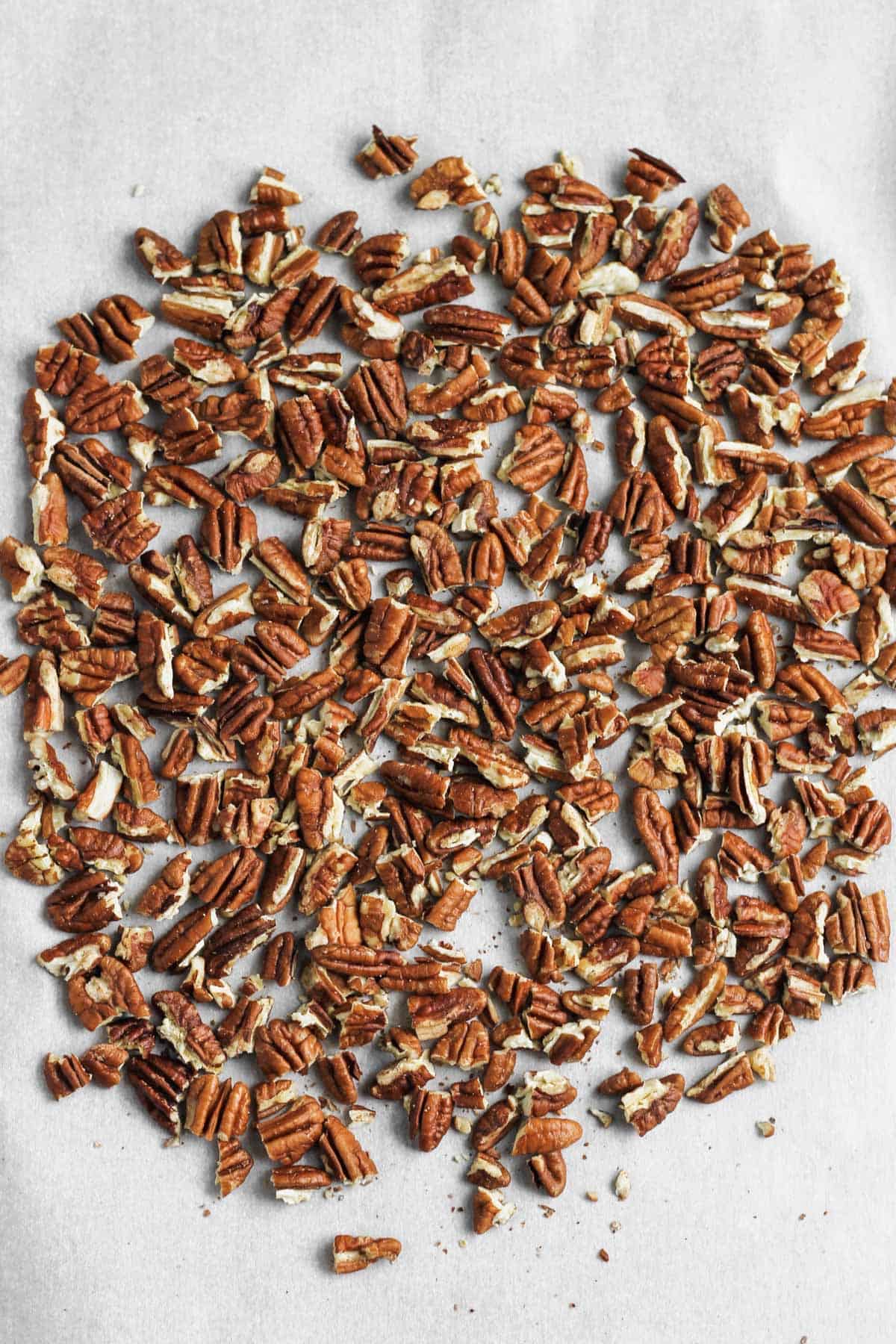 Toasted pecans on a parchment-lined sheet pan.