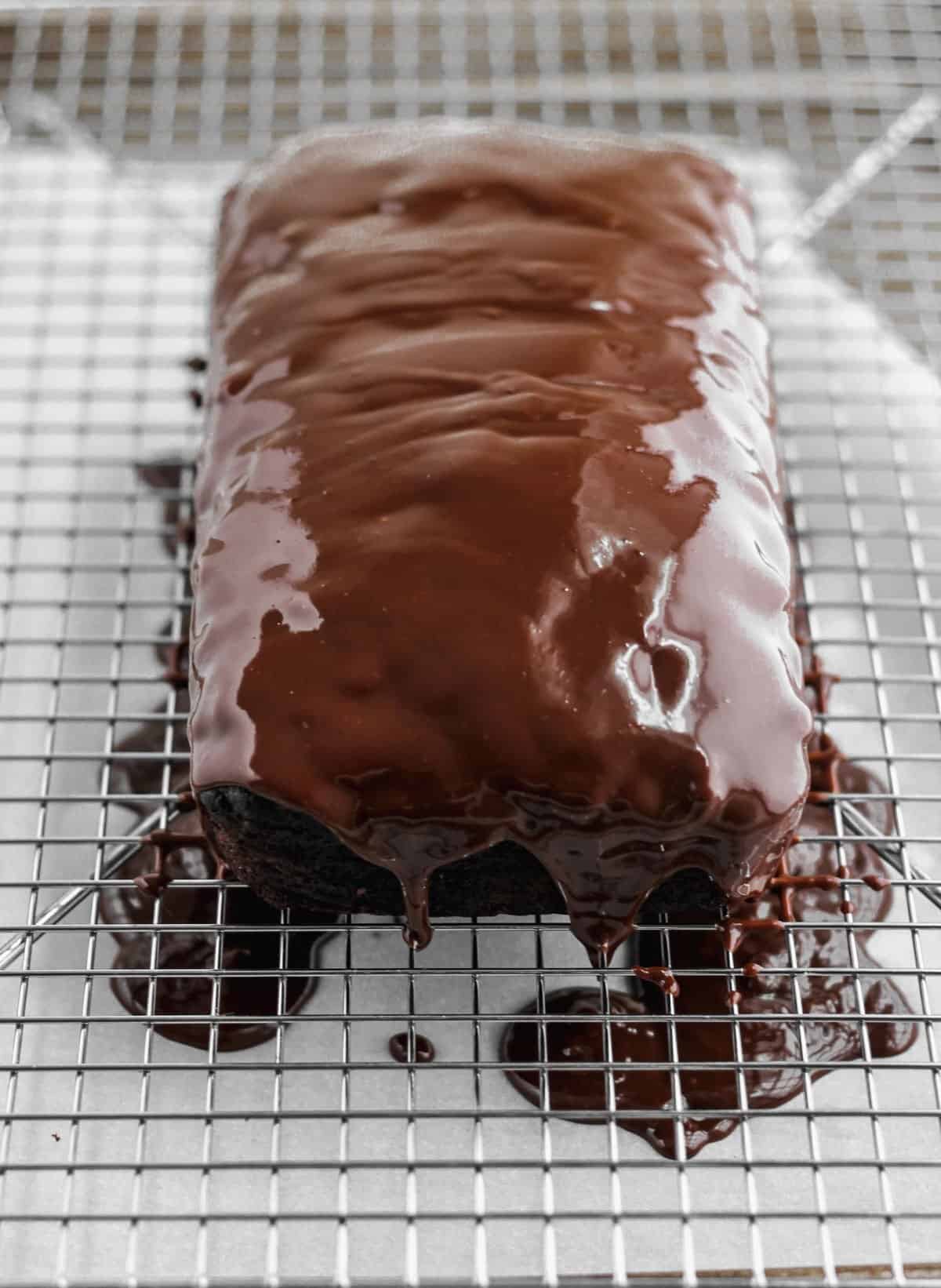 Chocolate glaze poured over the chocolate zucchini bread on top of a wire cooling rack.