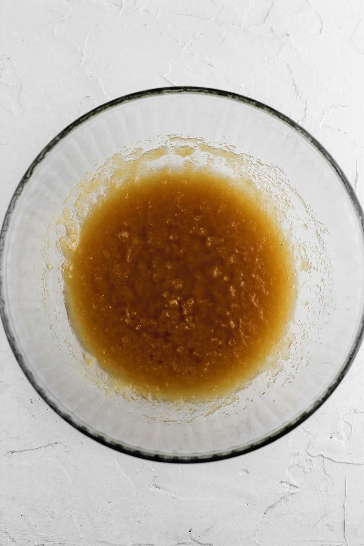 Melted butter, oil, and brown sugar combined in a glass mixing bowl.