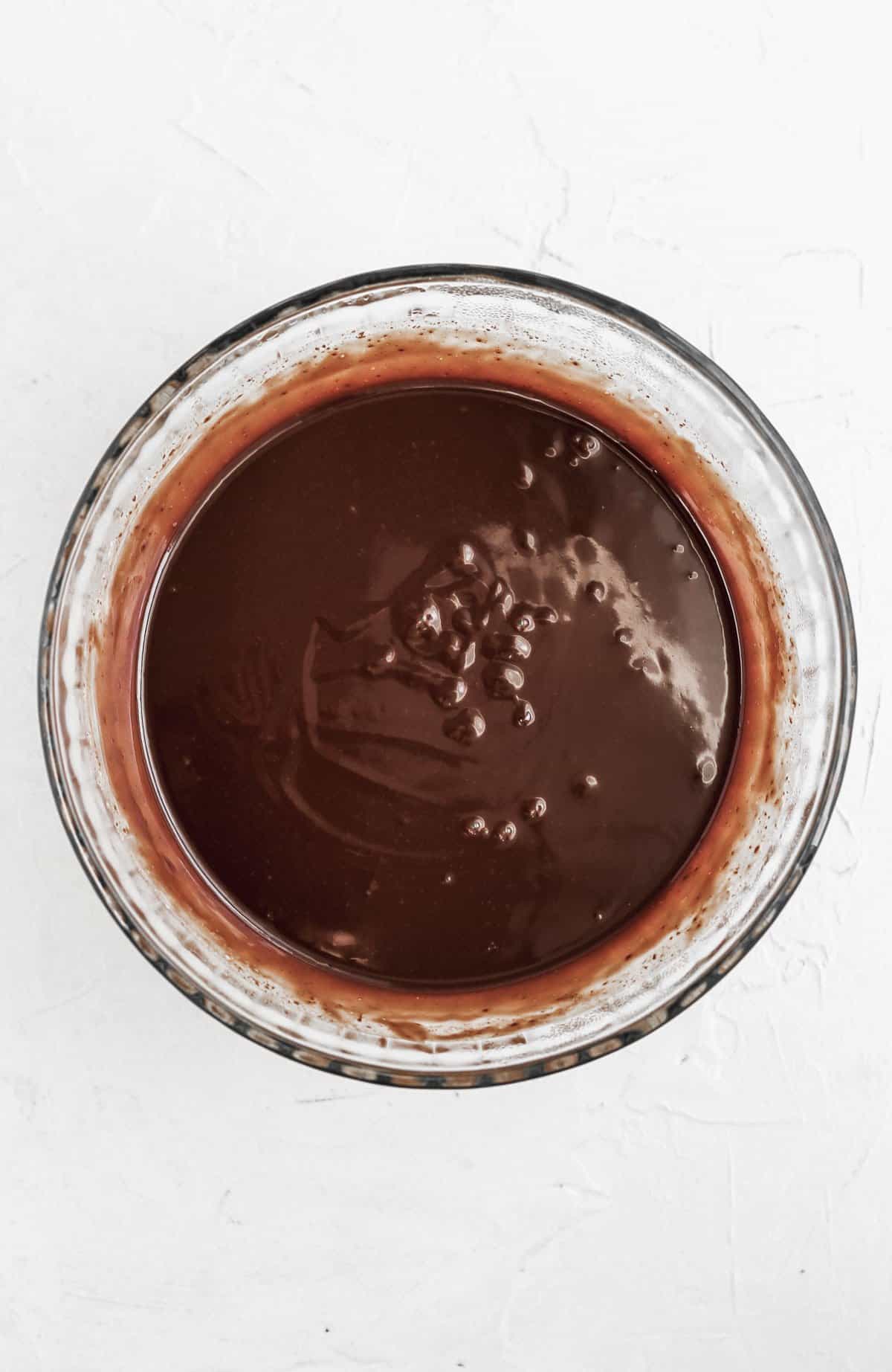 Smooth and shiny chocolate ganache in a glass bowl.