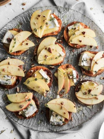 Sweet potato crostini on a glass plate with a grey napkin underneath.