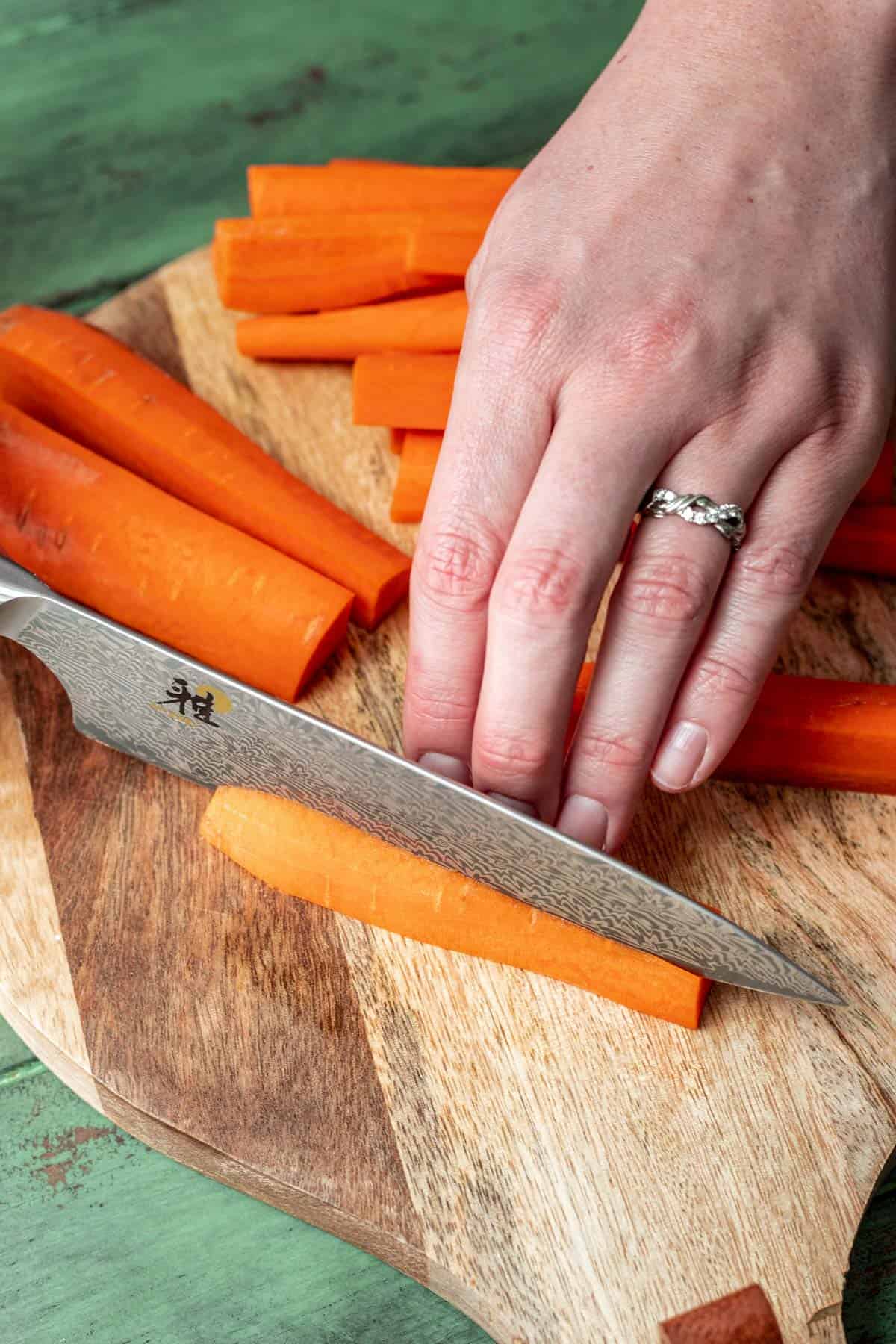 Cutting the quarters in half to create thin carrot fries.