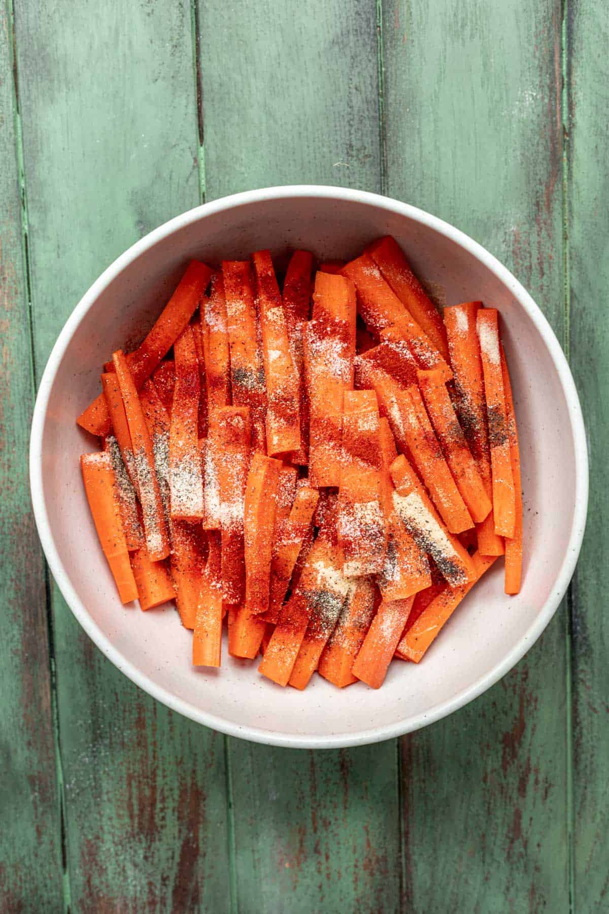Carrots seasoned in a mixing bowl.