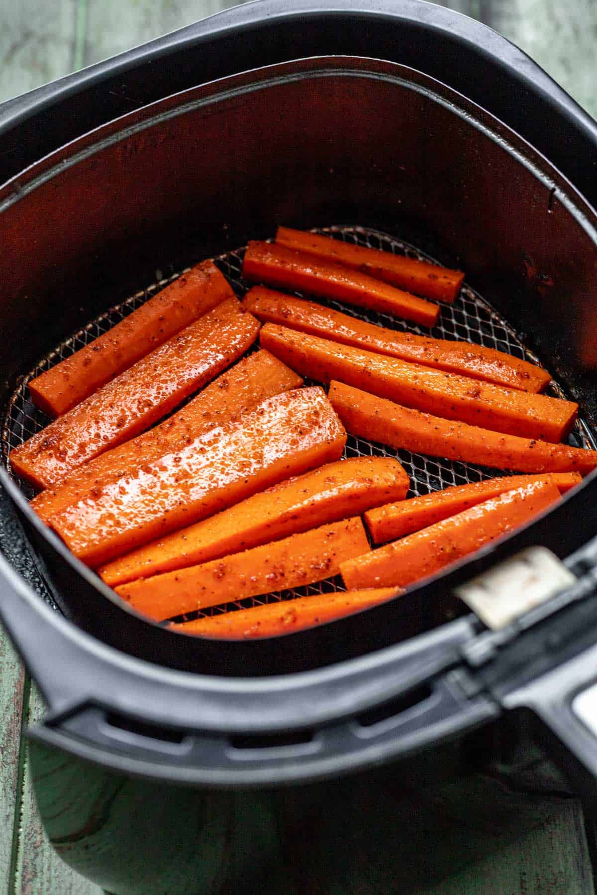 Raw carrots placed in an air fryer basket.