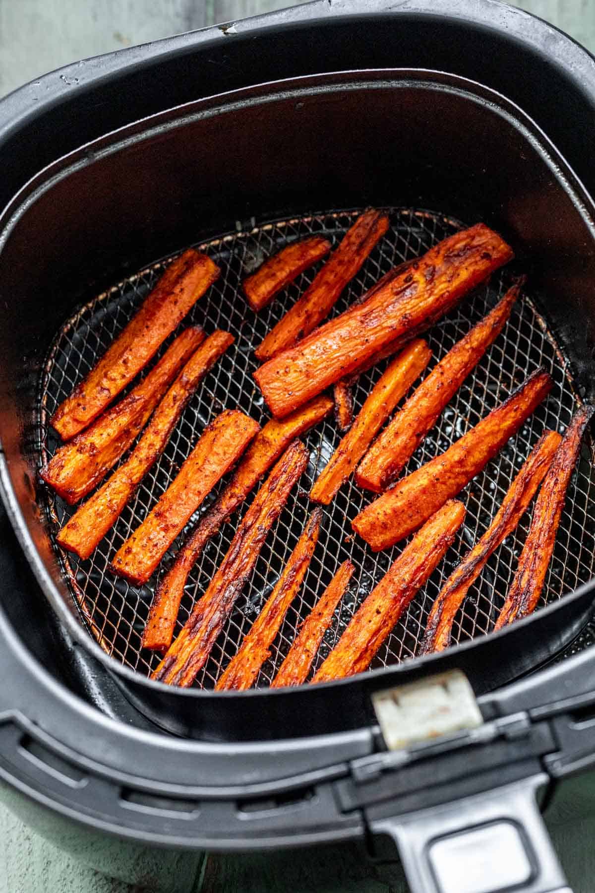 Cooked carrots in an air fryer basket.