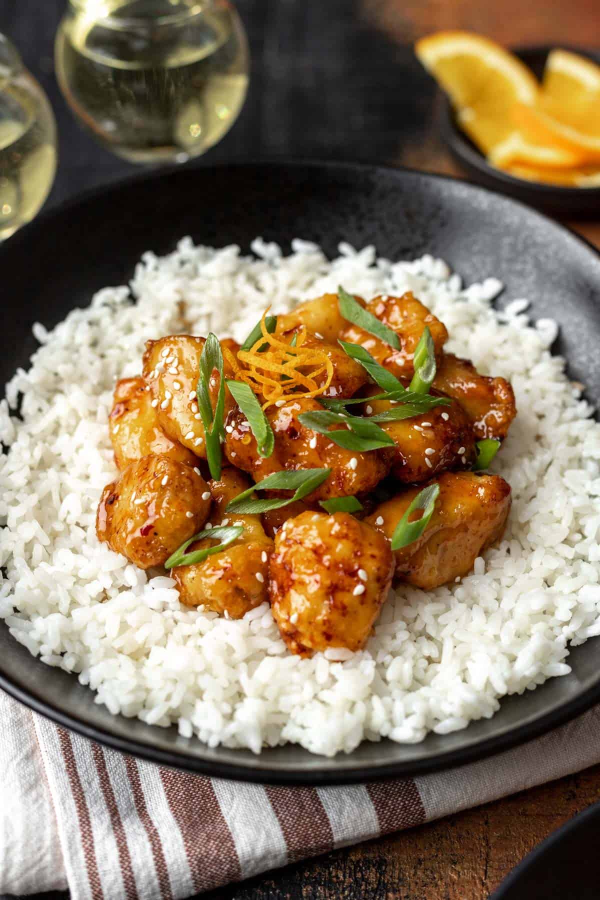 Air fryer orange chicken topped with orange zest, sesame seeds, and green onions.