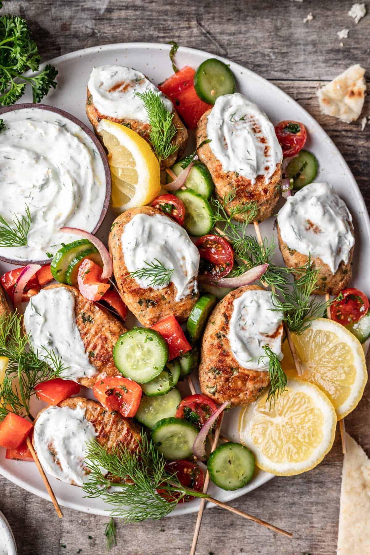 Mediterranean chicken meatballs on a serving platter with jerusalem salad and lemon dill yogurt sauce.