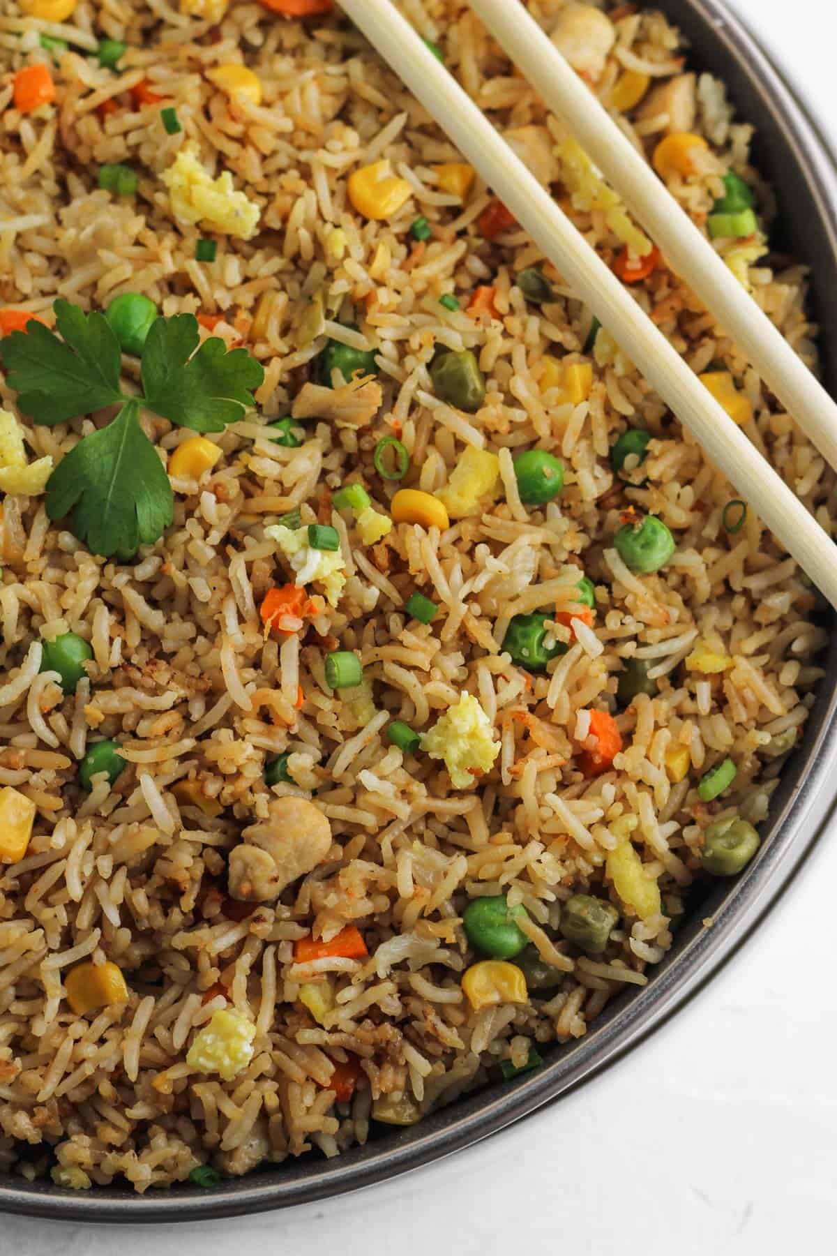 Close up of instant pot chicken fried rice garnished with parsley in a gray bowl.