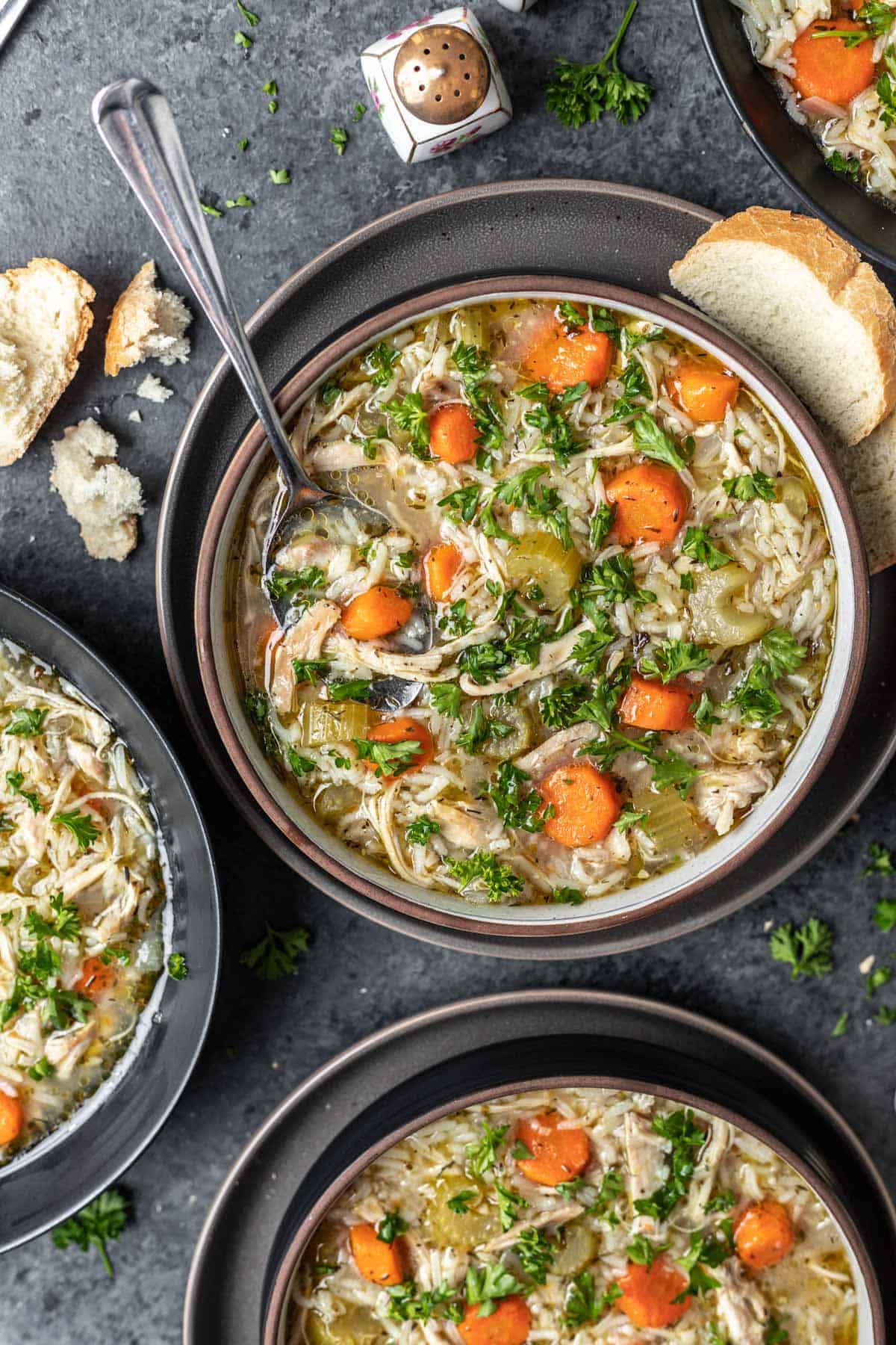 Instant pot chicken rice soup in 3 bowls with a side of crusty bread.