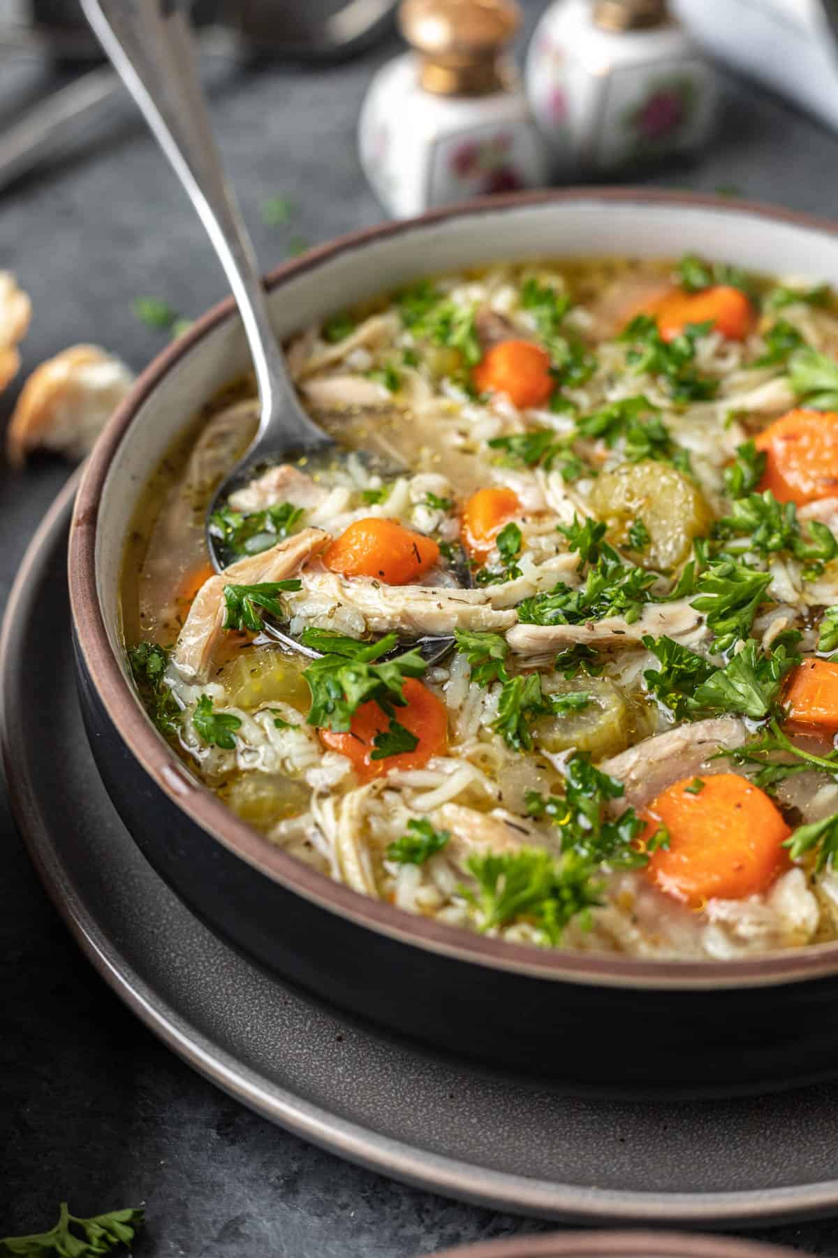 A spoon scooping up some instant pot chicken rice soup out of a bowl.