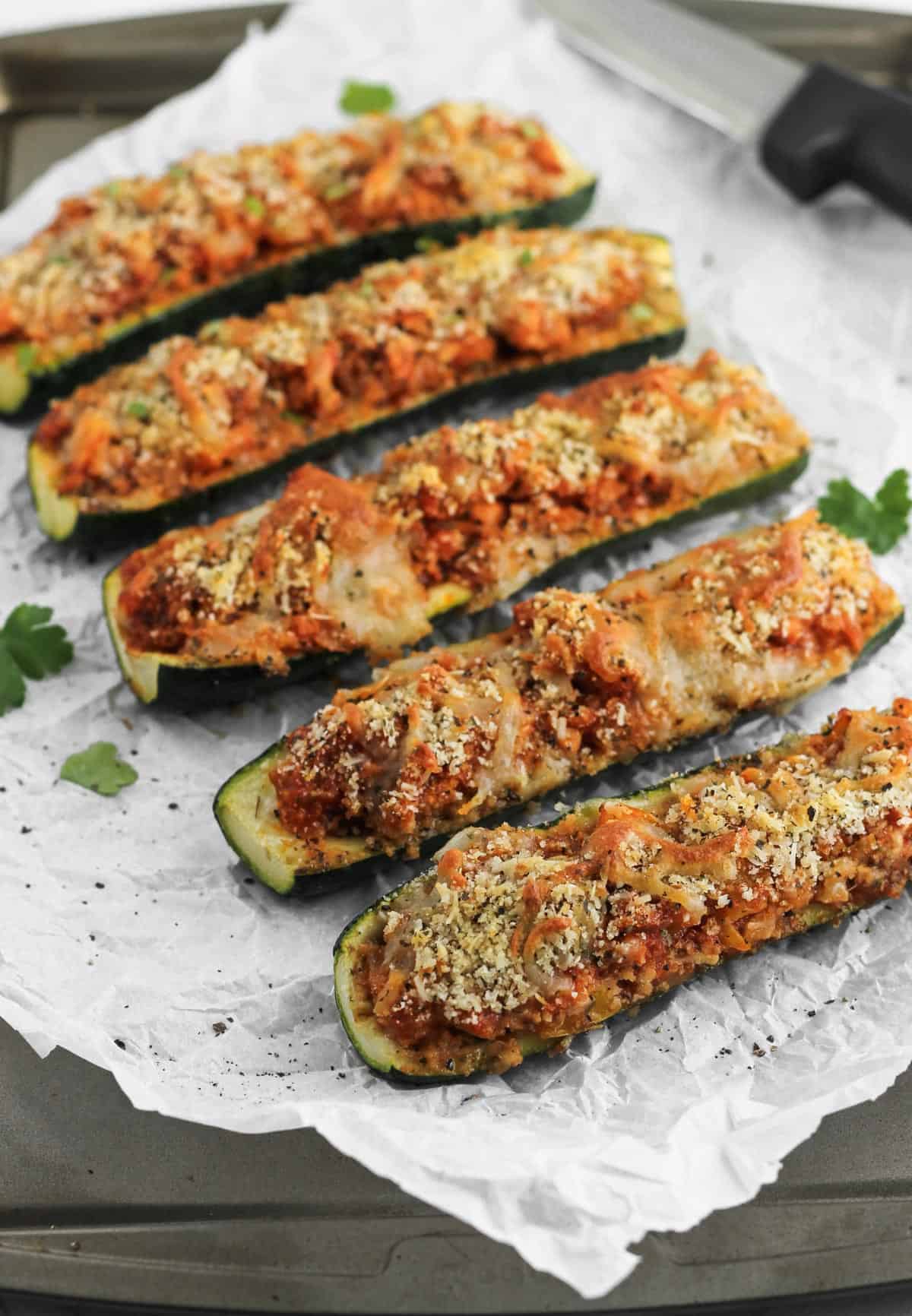 Italian zucchini arranged on a baking tray layered with parchment paper and parsley garnish.