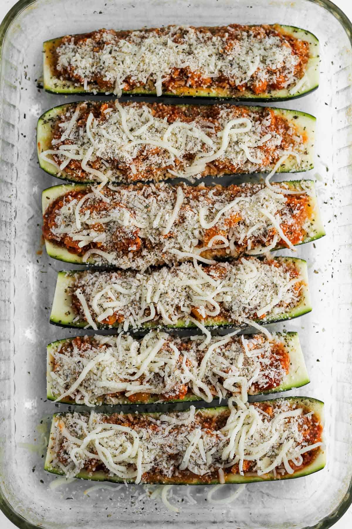 6 halved zucchini filled with italian filling and topped with parmesan cheese, mozzarella, and breadcrumbs.