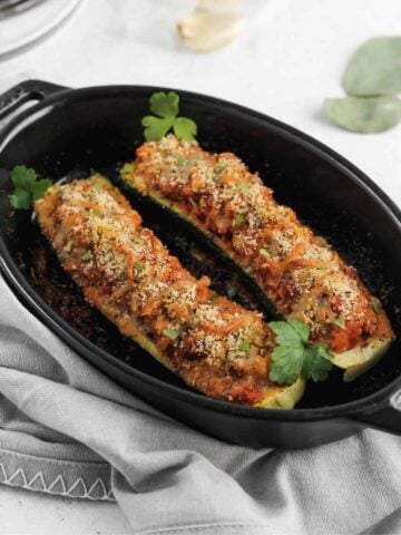 Italian zucchini garnished with parsley in a black baking dish.
