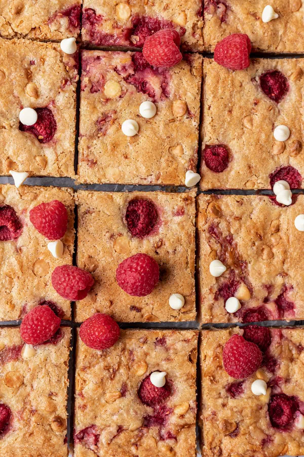 White chocolate raspberry blondies topped with fresh raspberries and cut into bars.